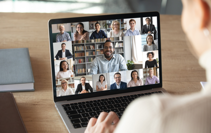 Someone looking at a laptop screen with multiple people on a virtual meeting.